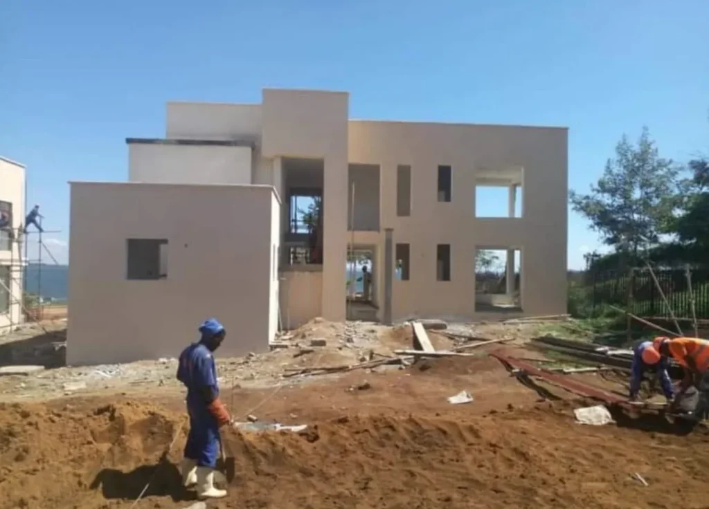 Plastered two-storey house with stepped flat-roofed volumes and a worker in the foreground