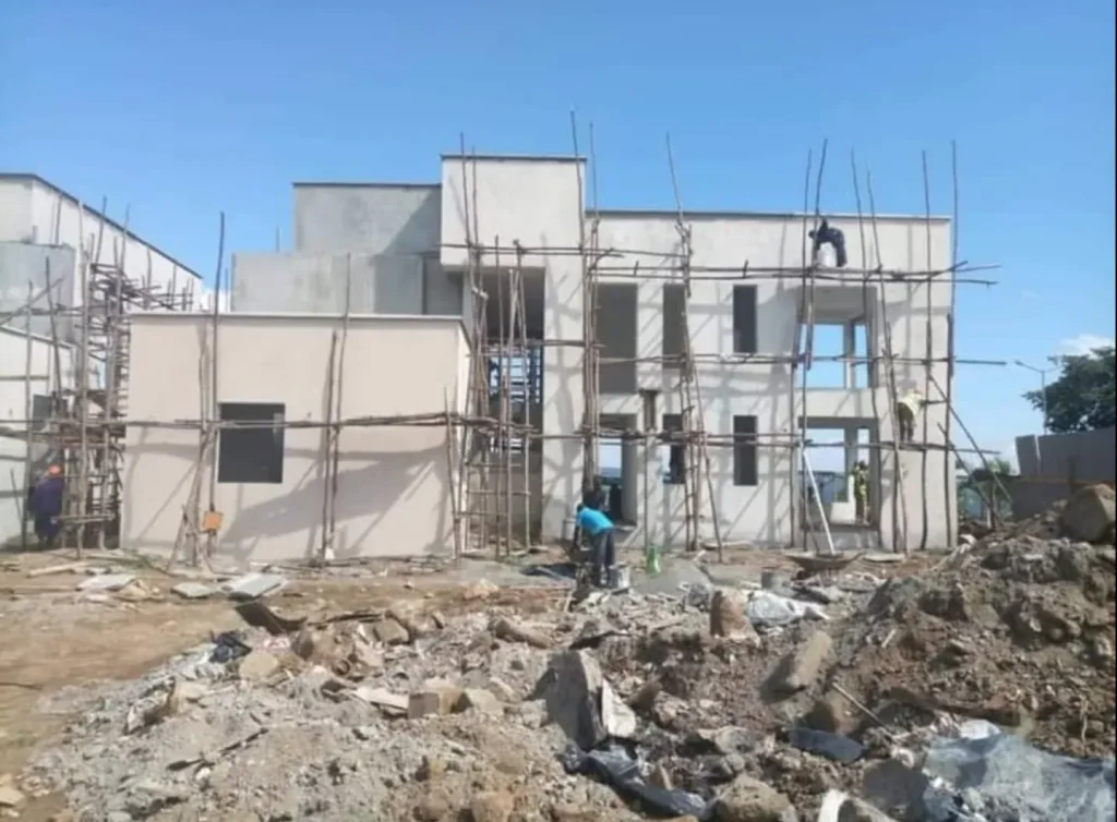 Two-storey house with white plastered walls and workers on timber scaffolding