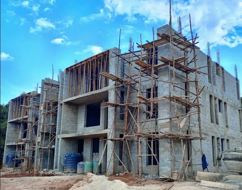 Three-storey concrete block building under construction with timber scaffolding