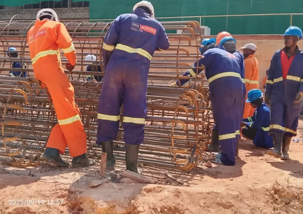 Workers assembling round reinforcement cages for pile foundations