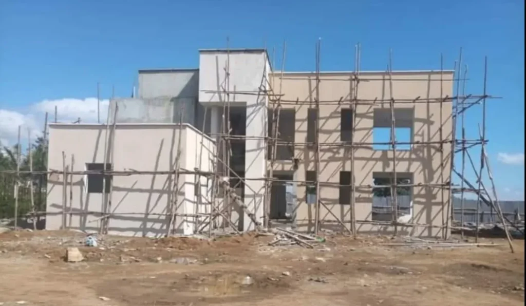 Two-storey house with timber scaffolding around the plastered facade