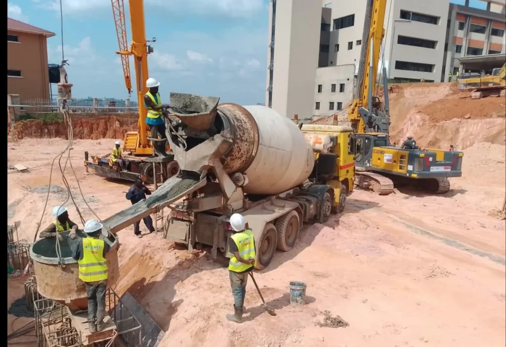 Concrete truck pouring a pile foundation beside a piling rig