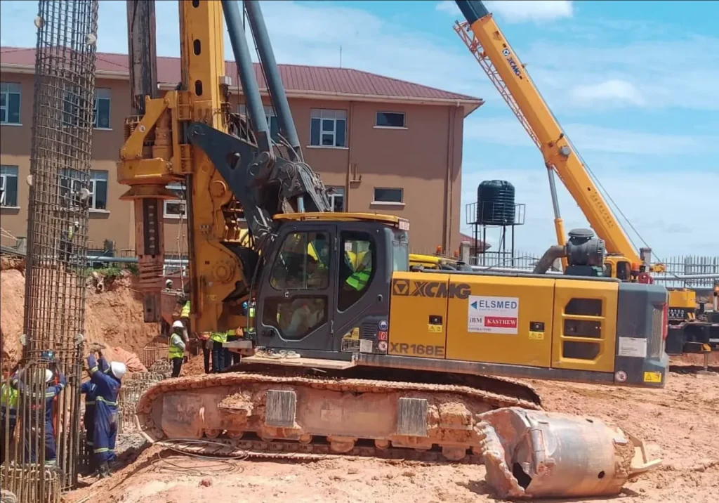 Crane lifting a tall reinforcement cage beside a piling rig