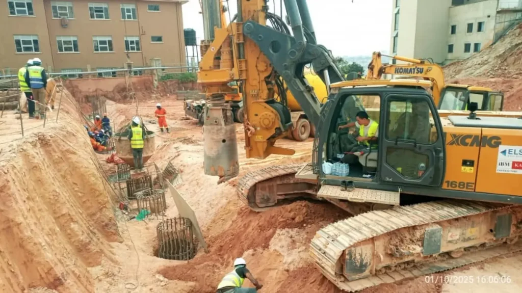 Piling rigs and an excavator in a foundation excavation beside existing buildings