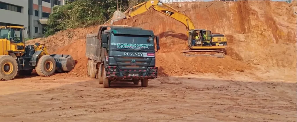 Wheel loader, tipper truck and excavator at a red earth cut face
