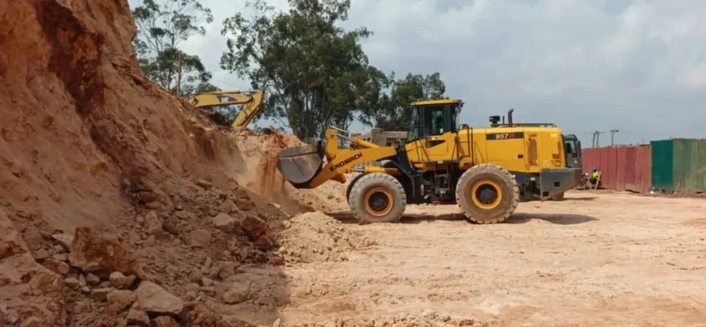 Yellow wheel loader working at the base of a high earth cut