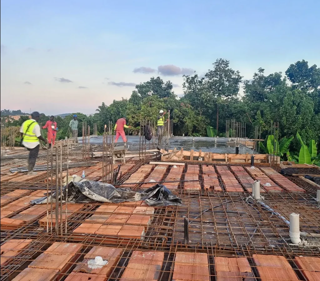 Workers in hi-vis vests laying reinforcement bars over rows of clay blocks for a floor slab
