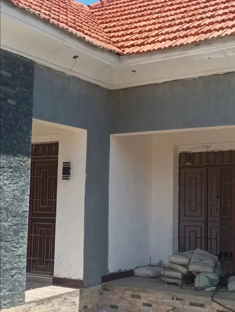 Entrance of a bungalow with panelled double doors and dark stone cladding