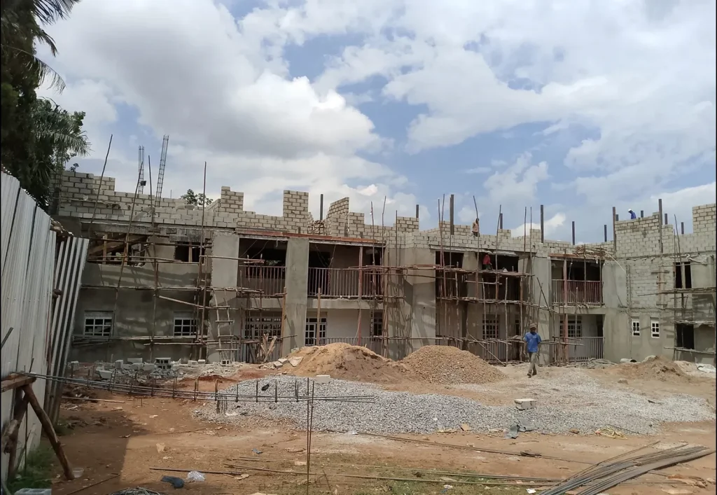 Long two-storey block building with scaffolding and heaps of gravel in front