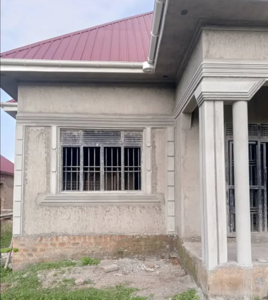 Side wall of a plastered house with a barred window and column