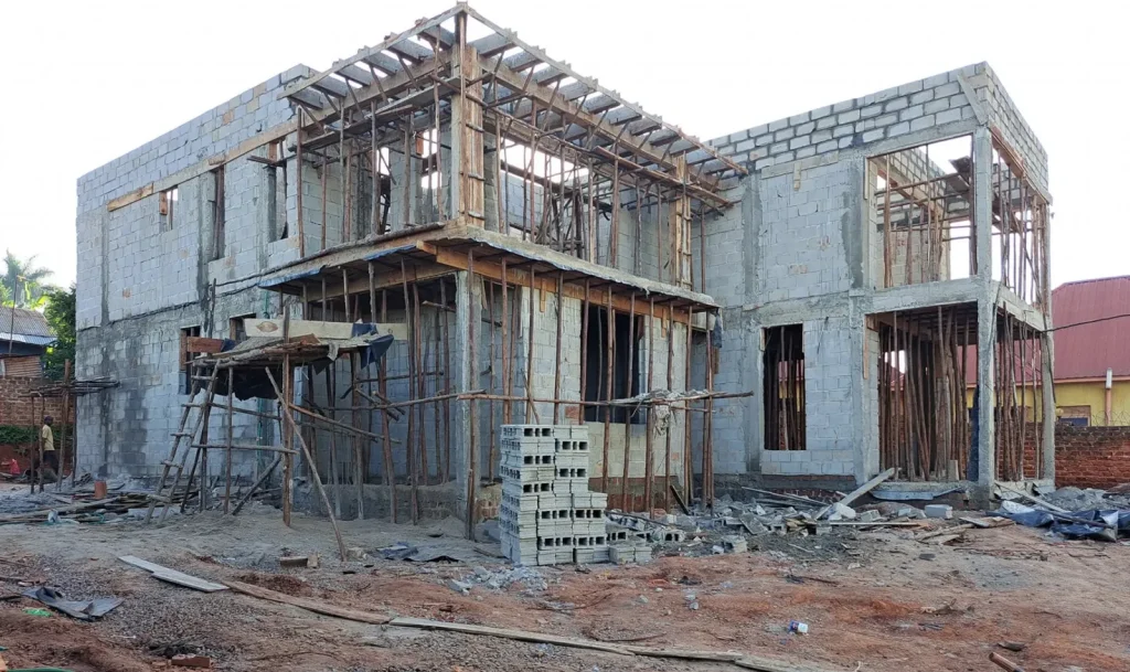 Two-storey concrete block house with its upper floor propped on timber supports