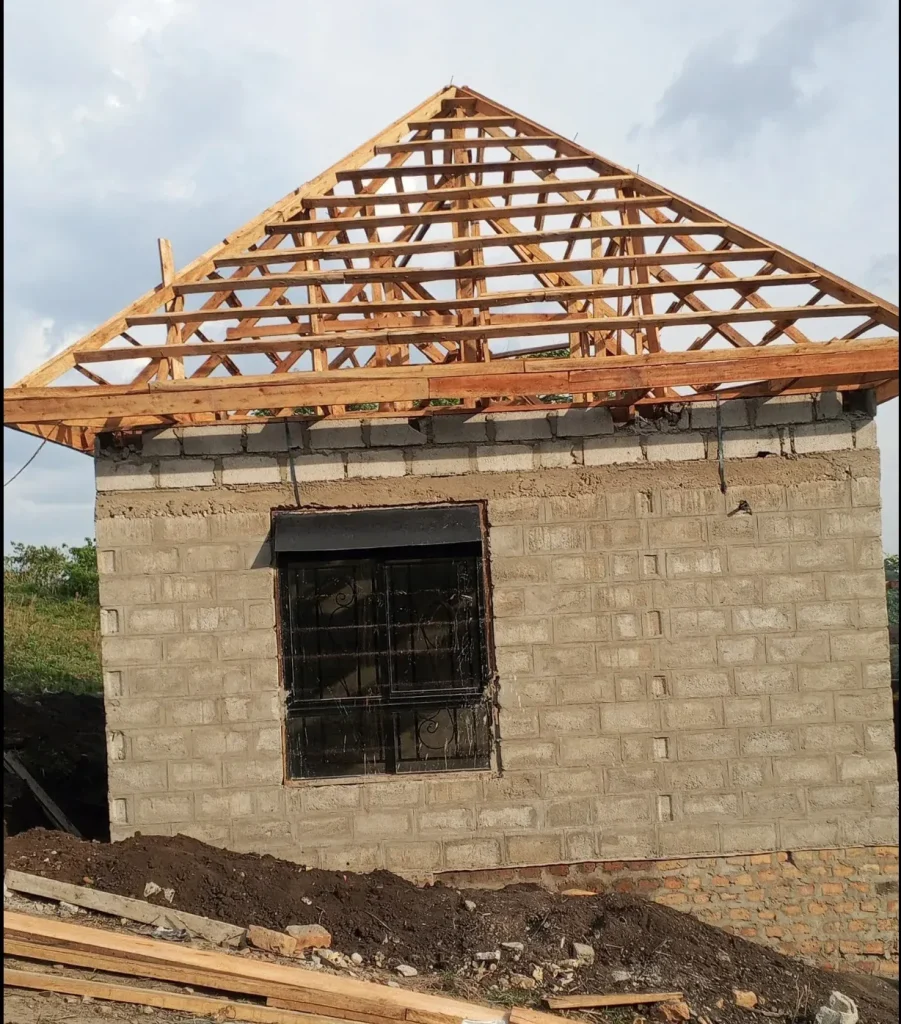 Block house corner with a barred window and a timber hip roof truss above