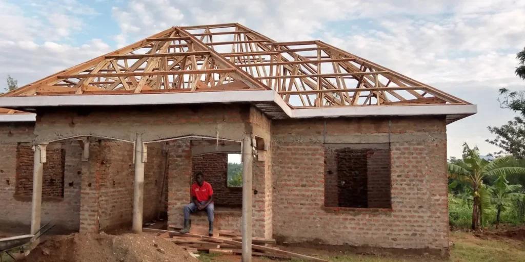 Front of a brick house with a completed timber roof frame and columns