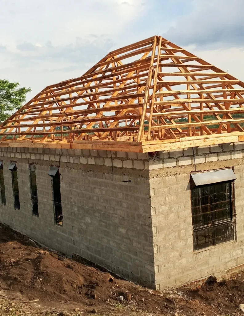 Side of a long block house with a timber hip roof frame on top