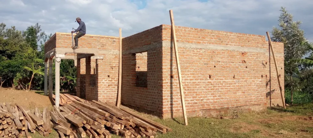 Brick house walls with a roofer standing at the top, before the roof trusses go up